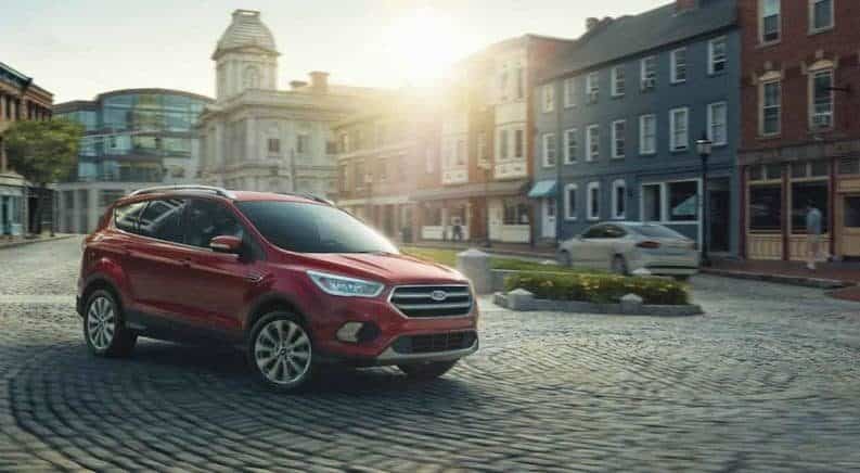 A red 2018 Ford Escape from Ford Dealerships rounding a cobble stone rotary