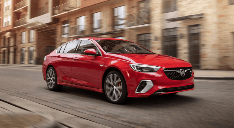 Red 2019 Buick Regal sedan with out of focus brick building and road