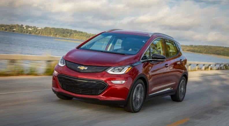 Red 2019 Chevy Bolt driving by lake