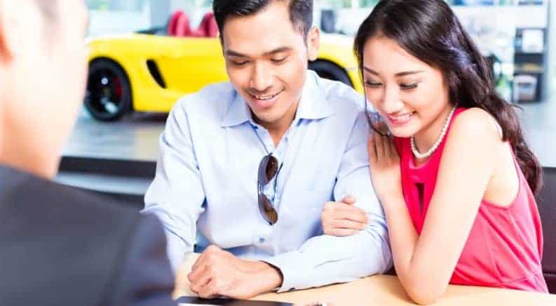 A young couple signs the paper work for their buy here pay here car loan