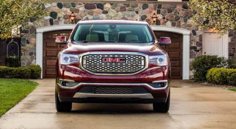 A red 2019 GMC Acadia Denali in front of a stone house
