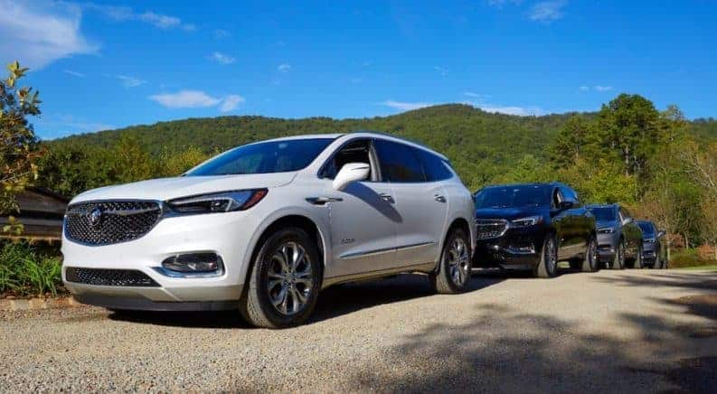 A white 2019 Buick Enclave Avenir with other cars parked on a dirt road