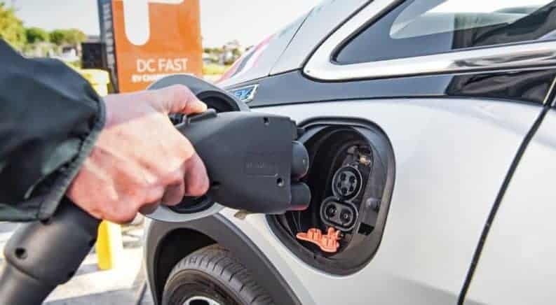 A hand goes to plug in a silver 2019 Chevy Bolt EV