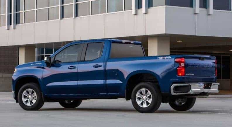 A dark blue 2019 Chevy Silverado in front of a glass building