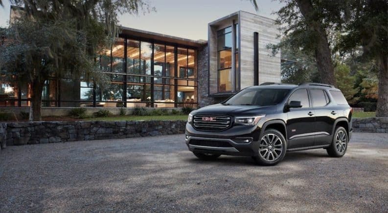 A black 2019 GMC Acadia All Terrain in front of a modern glass building