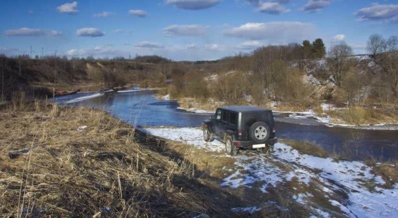 A black Jeep Wrangler in a river