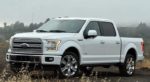A white used Ford F-150 in a grassy field