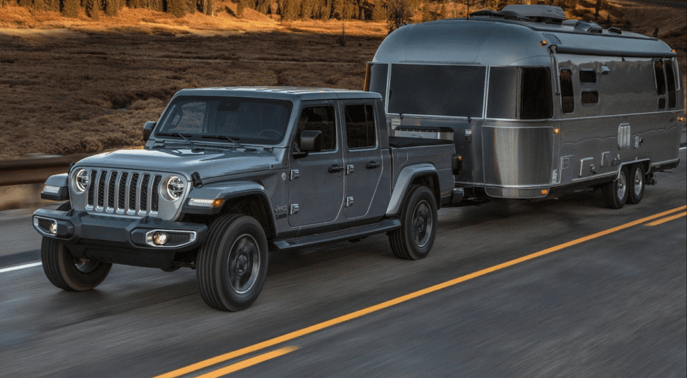 A silver 2020 Jeep Gladiator tows an Airstream trailer on a desert highway