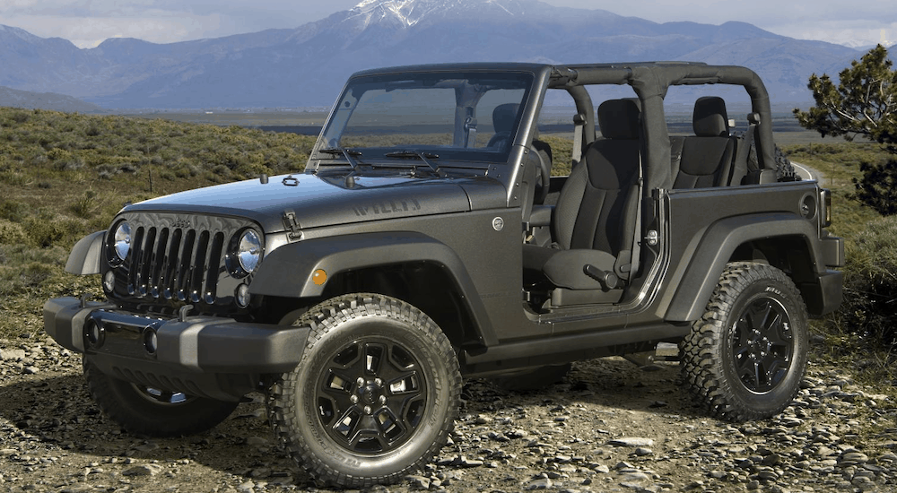 A doorless dark grey 2018 Jeep Wrangler is shown parked with a mountain in the distance. You can find a used Jeep Wrangler for sale at at CDJR dealer.