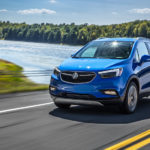 A blue 2019 Buick Encore driving by a lake