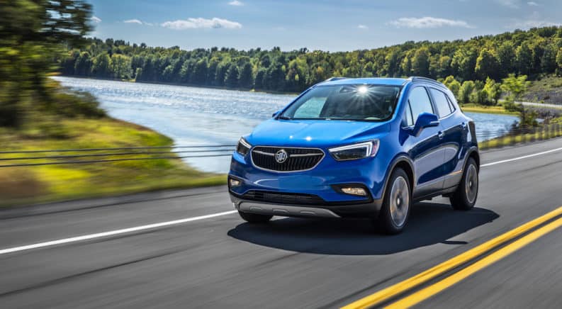 A blue 2019 Buick Encore driving by a lake