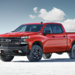 A red 2019 Chevy Silverado is shown on salt flats with blue sky behind it.