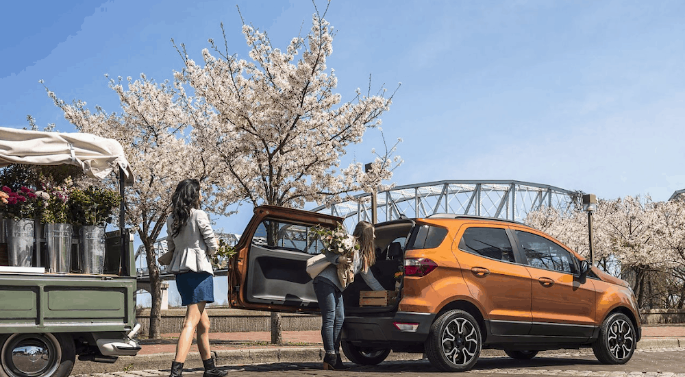 Women load flowers in to the back of a copper 2019 Ford Ecosport. In many aspects the Ecopsport wins when comparing the 2019 Ford Ecosport vs 2019 Jeep Renegade.