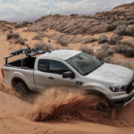 A silver 2019 Ford Ranger is taking a sharp corner in the desert with sand spraying. You can find Ford trucks for sale at a Ford Dealer.