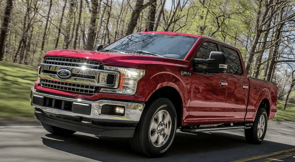 A ruby red 2019 Ford F-150 is driving past trees.