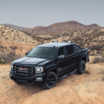A black 2019 GMC Sierra with black trim and wheels is shown in a desert.