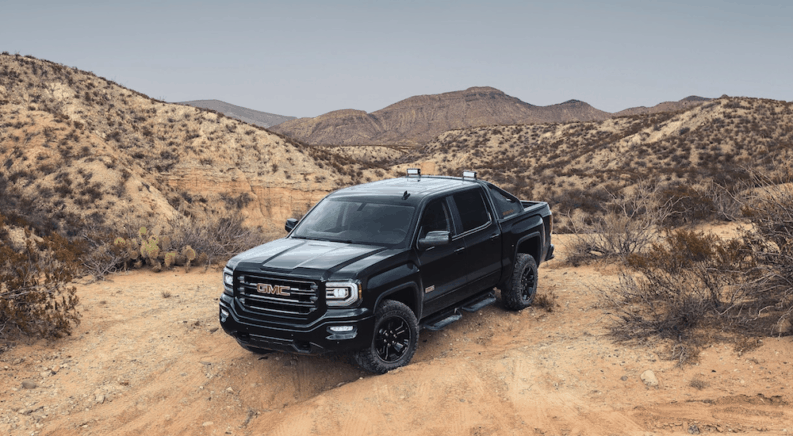 A black 2019 GMC Sierra with black trim and wheels is shown in a desert.