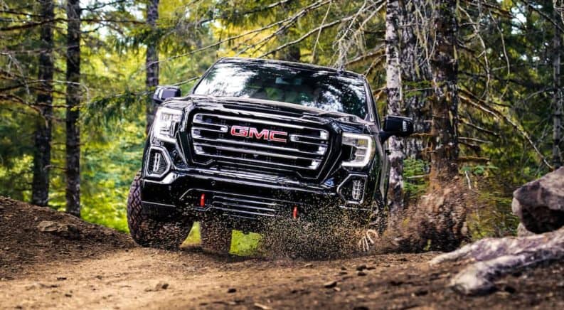 A black Sierra crashes through mud and the competition of 2019 GMC Sierra 1500 vs 2019 Ram 1500