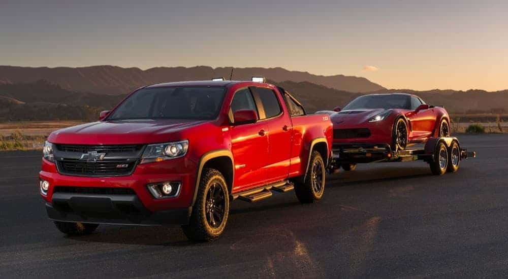 A red 2019 Chevy Colorado is towing a red Corvette. The Colorado can tow much more when comparing the 2019 Chevy Colorado vs 2019 Nissan Frontier.