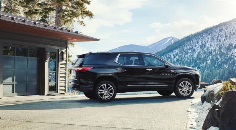 A black 2019 Chevy Traverse is parked at a house with a mountain view.