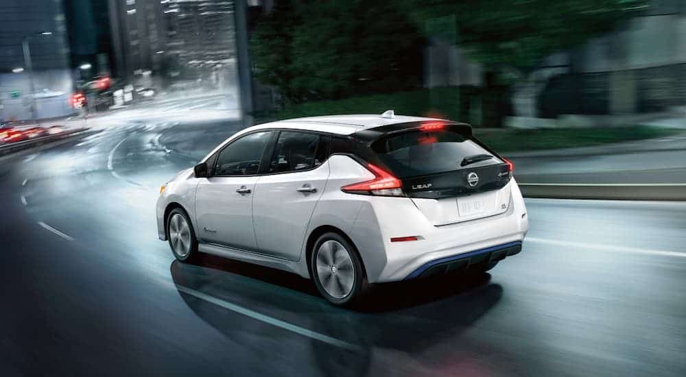 A white 2019 Nissan Leaf is driving in the rain.