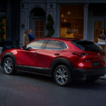 A red 2020 Mazda CX-30 is parked outside shops. It is Mazda's future release in current auto news.