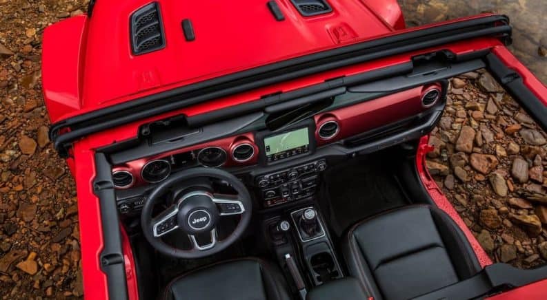 The interior of a red 2018 Jeep Wrangler is shown from above the roof rails. The Wrangler is an option for a Jeep Lease.