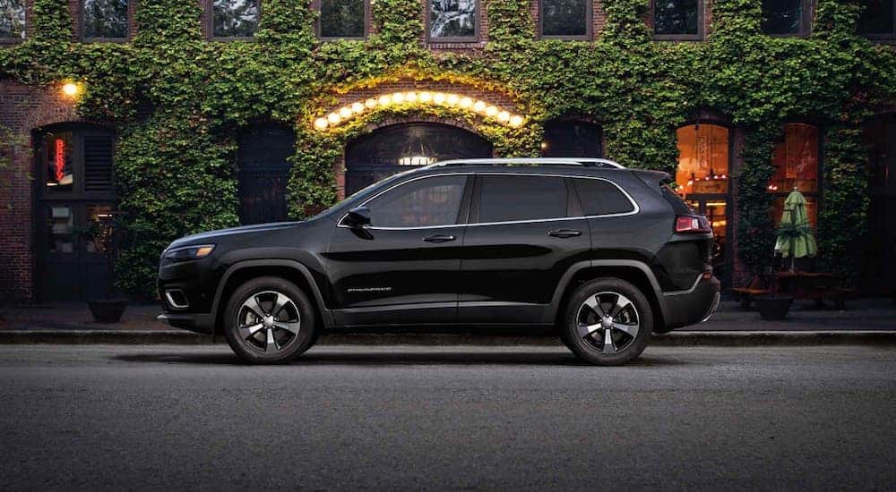 A black 2019 Jeep Cherokee is parked in front of an ivy covered brick building.