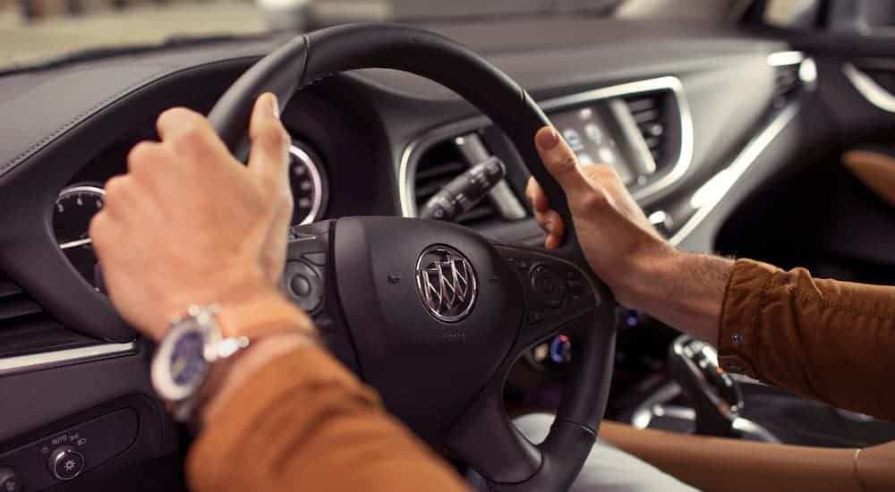 Hands are on a close up of the 2019 Buick Enclave's steering wheel. Compare interiors when looking at the 2019 Buick Enclave vs 2019 Chevy Traverse.
