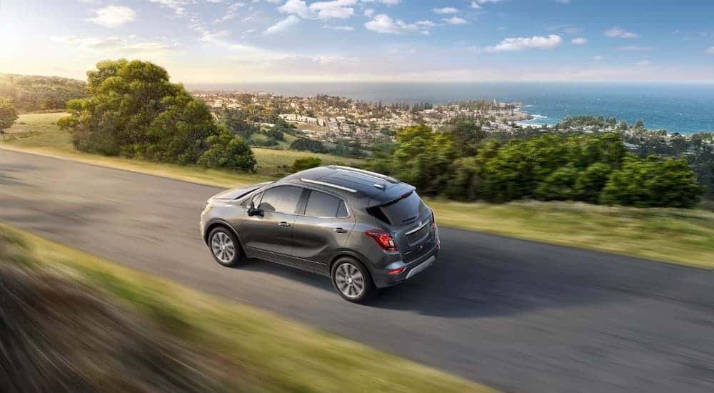 A grey 2019 Buick Encore is on a narrow road high above a bay. Check out performance when comparing the 2019 Buick Encore vs 2019 Ford EcoSport.