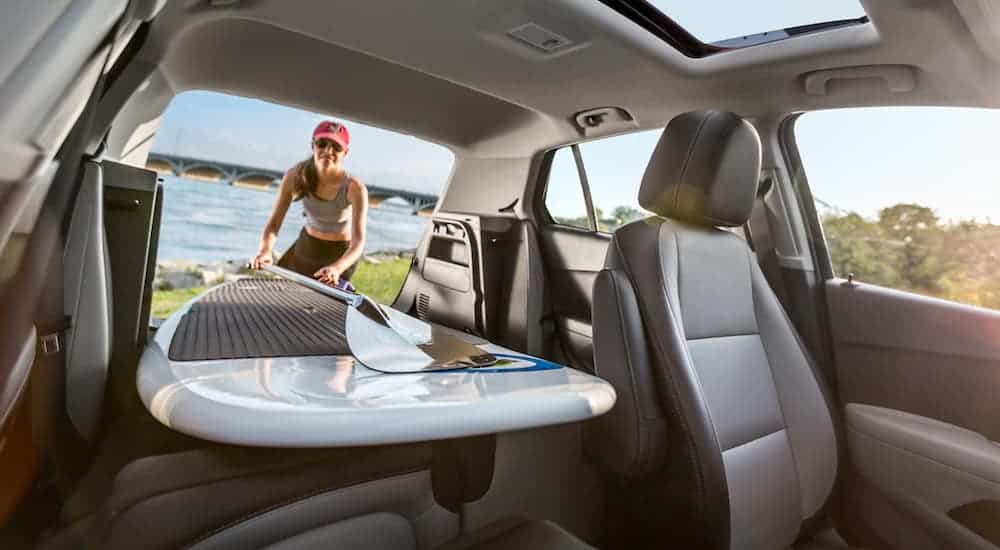 A woman loading her paddle board is shown from the inside of a 2019 Chevy Trax, whihc wins when comparing the 2019 Chevy Trax vs 2019 Hyundai Kona.