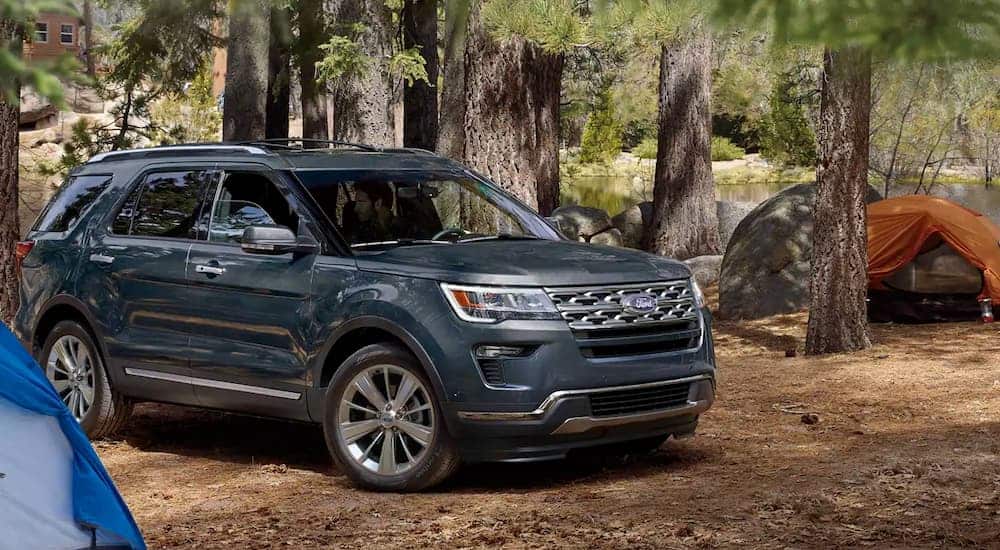 A dark grey 2019 Ford Explorer, which wins when comparing the 2019 Ford Explorer vs 2019 Toyota Highlander for off-road capabilities, is parked at a campsite.