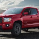 A red 2019 GMC Canyon is parked with a sun flare in the background.