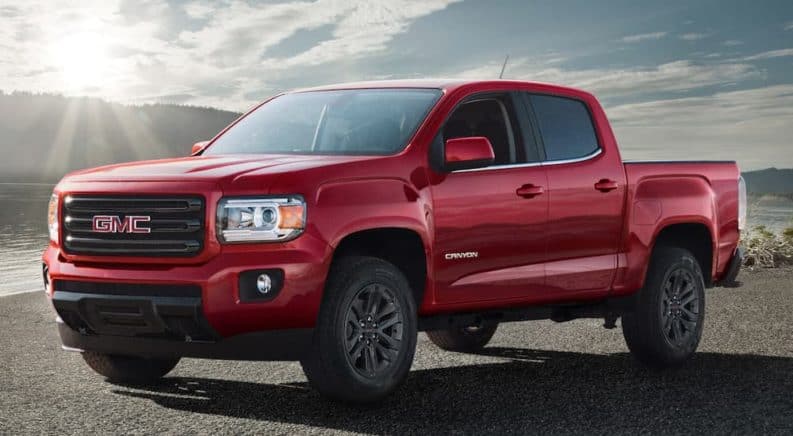 A red 2019 GMC Canyon is parked with a sun flare in the background.