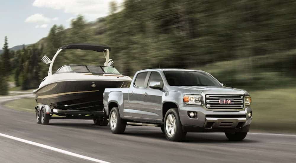 A silver 2019 GMC Canyon is towing a boat. Check out performance when comparing the 2019 GMC Canyon vs 2019 Ford Ranger.