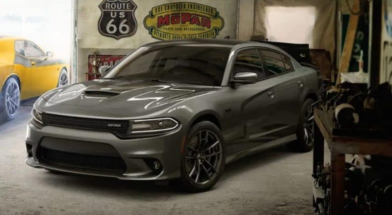 A grey 2019 Dodge Charger is parked in a garage with a Challenger leaving behind it. They can be found at any of the Dodge dealers in your area.