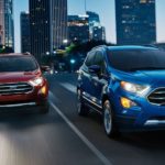A red and a blue 2019 Ford Ecosport are driving through the city at night.