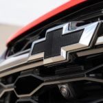 A close up of the Chevy logo in black is shown on a red vehicle.