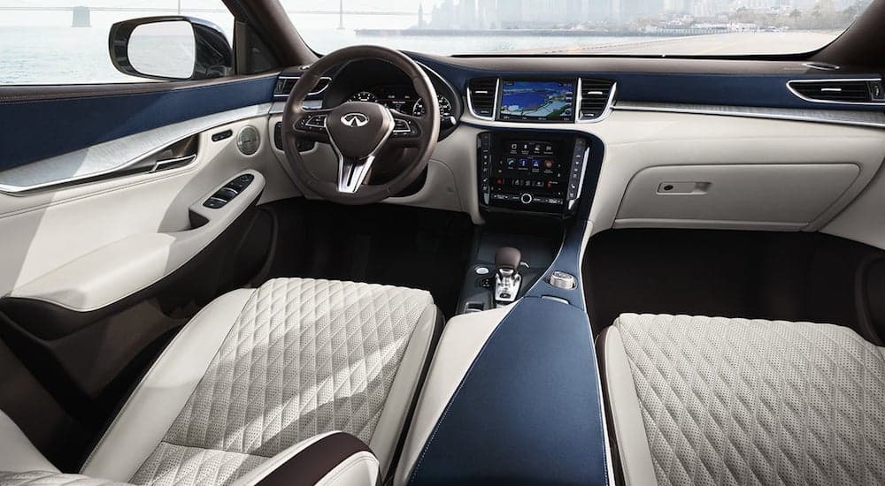 The front interior of the QX50, with light tan leather and dark grey trim, is shown. 