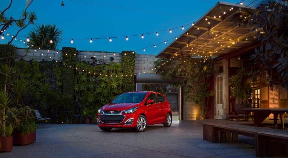 A 2019 Chevy Spark is shown parked with a night sky and lights in the background near a local Chevy dealership.