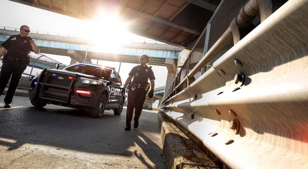 Two officers are walking away from their 2020 Ford Explorer Interceptor under an overpass.