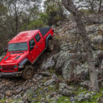 The 2020 Jeep Gladiator is shown driving down a rock hill in the woods.