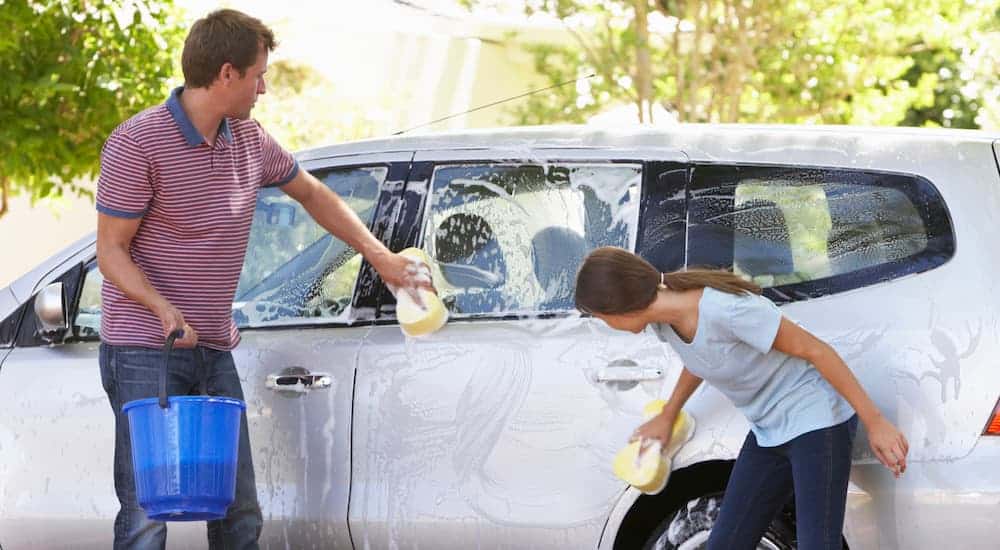 A father and daughter are washing their used car.