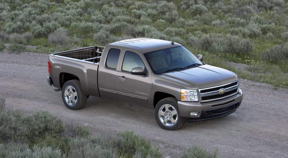 A grey 2009 Chevy Silverado, a popular model for used trucks, is driving on a dirt road.
