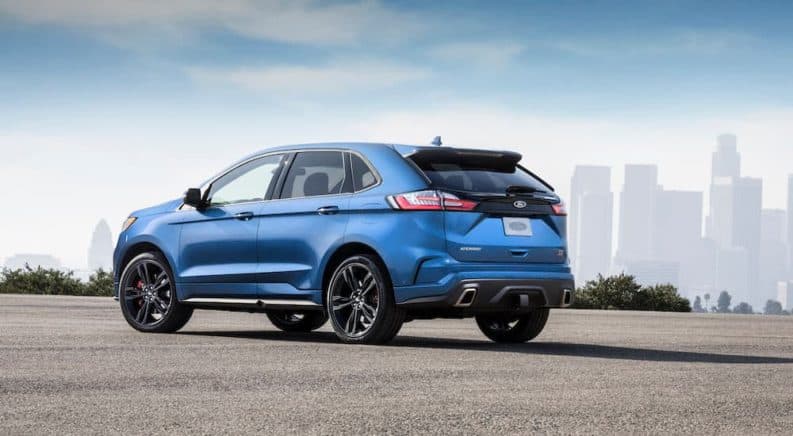 A blue 2019 Ford Edge, which wins when comparing the 2019 Ford Edge vs 2019 Chevy Blazer, is parked in front a city skyline.