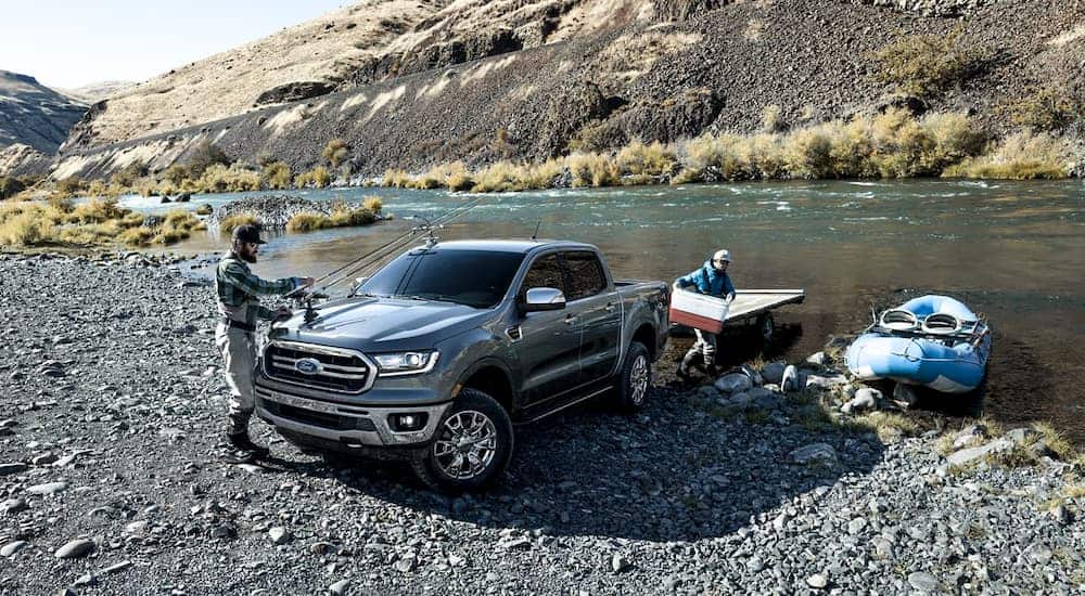 A grey 2019 Ford Ranger is backing a trailer for a boat in the river.