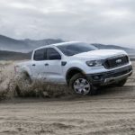 A white 2019 Ford Ranger is driving in the sand. Check out base level performance when comparing the 2019 Ford Ranger vs. 2019 Chevy Colorado.