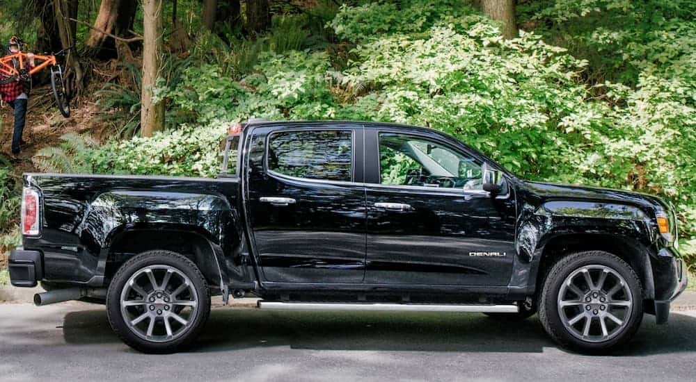 A black 2019 GMCV Canyon, which wins with engine options when comparing the 2019 GMC Canyon vs 2019 Toyota Tacoma, is parked in front of woods.