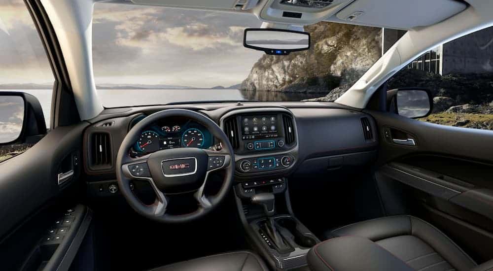 The black interior of a 2019 GMC Canyon is shown with a beach in the windshield view.