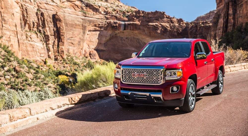 A red 2019 GMC Canyon, which wins when comparing the 2019 GMC Canyon vs. 2020 Jeep Gladiator, is in front of red rocks.
